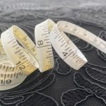 A woman using a fabric tape measure to check her bust circumference for a vintage dress