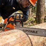 A sleek Supstable cordless chainsaw resting on a wooden workbench in a workshop.
